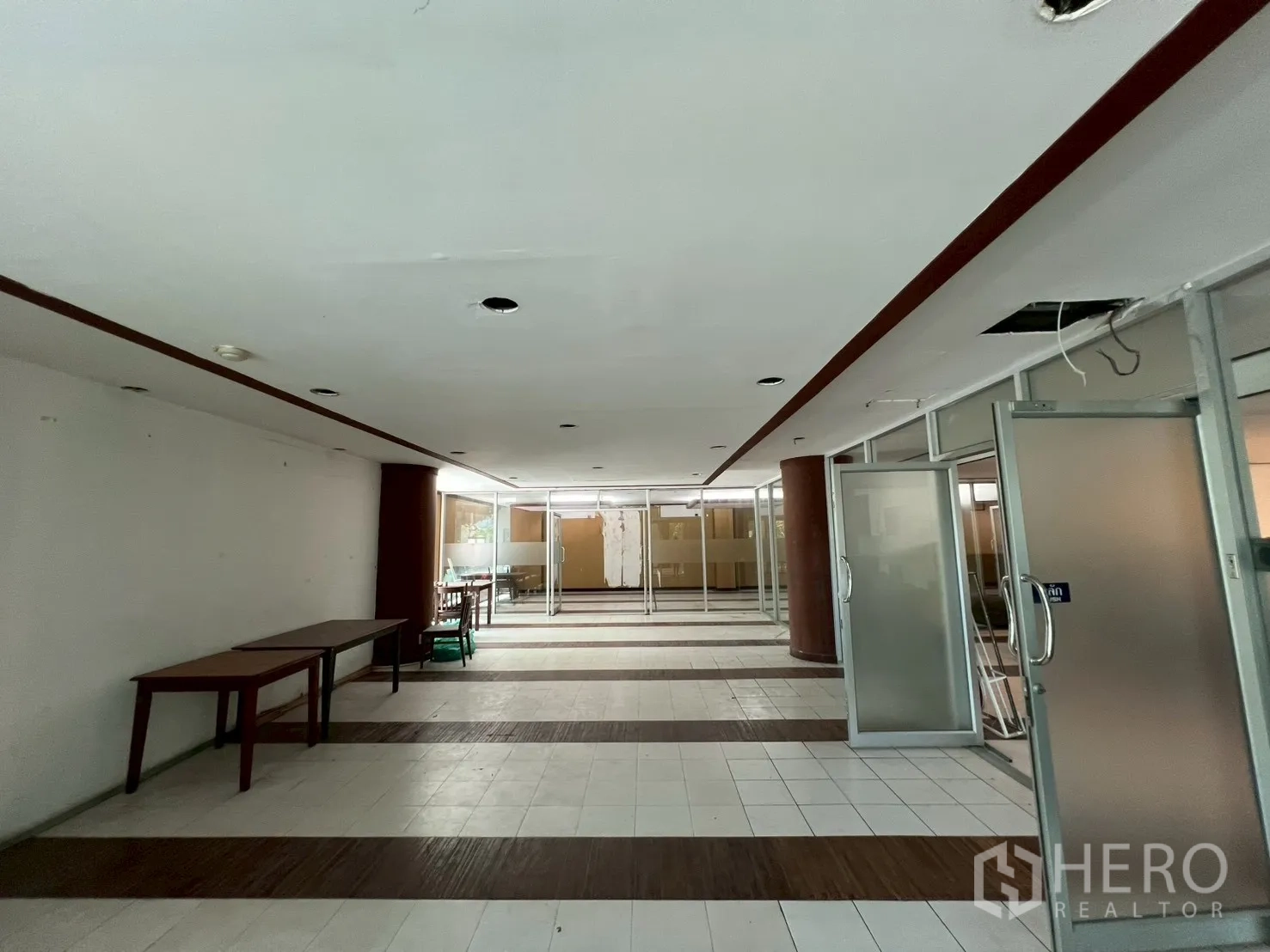 Retail Space for rent - Deep open-plan retail hall with tiled and wood inlay flooring, glass-partitioned rooms and sliding doors.