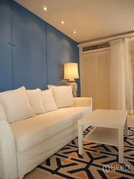 คอนโด ให้เช่าในKhlong Toei, Bangkok - พื้นที่นั่งเล่นโซฟาสีขาว ผนังบุสีน้ำเงิน และผ้าม่านโปร่ง