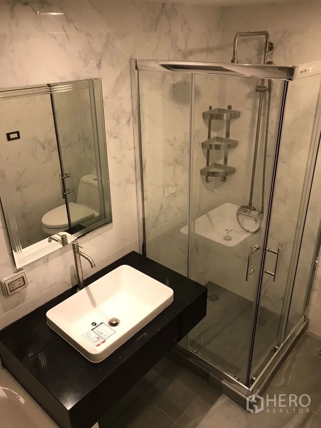 公寓 出租或出售在Khlong Toei, Bangkok - 浴室配玻璃淋浴间、方形台盆与黑色台面，墙面为大理石纹。