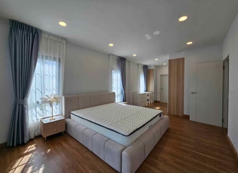 Detached House for rent in Bang Phli, Samut Prakan - Large master bedroom with upholstered bed, wood flooring, multiple windows and dressing/work area.