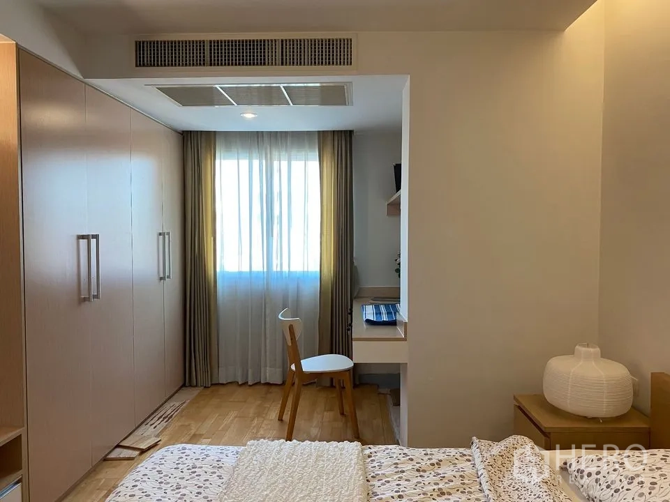 Condominium for rent or sale in Phra Khanong, Bangkok - Bedroom corner showing wall-length wardrobes, work desk and curtained window.