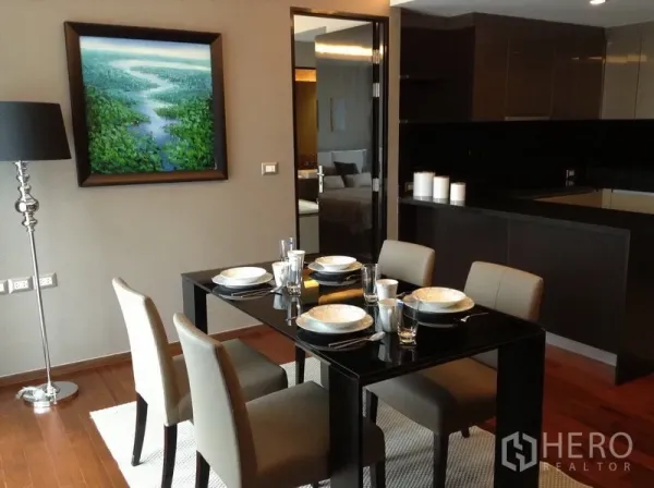 Condominium for rent in Watthana, Bangkok - View of a sleek four-seat dining table with wall art, floor lamp and access to the open kitchen.