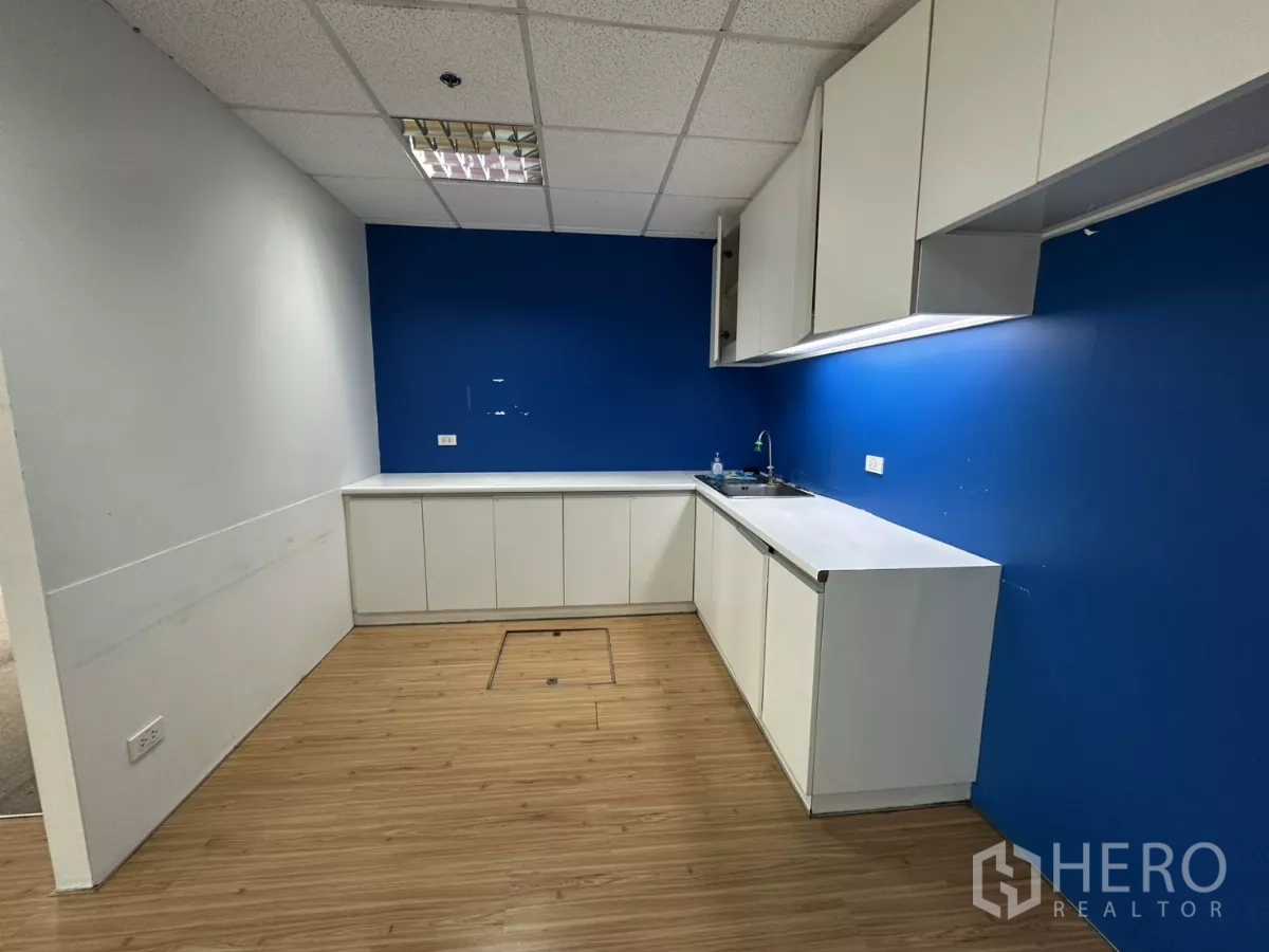 办公空间 出租在Watthana, Bangkok - 紧凑茶水间，白色橱柜、水槽与蓝色背景墙。