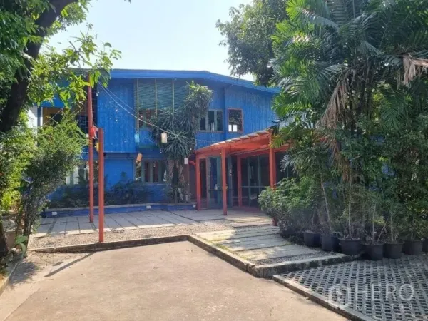 Detached House for rent in Khlong Toei, Bangkok - Front view of a blue two-storey detached house with red pergola, trees and driveway in Ekkamai.