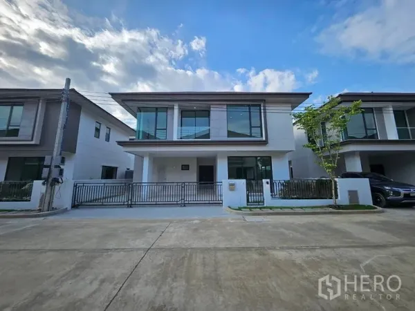 独立式住宅 出租在Saphan Sung, Bangkok - 街景视角的当代两层住宅，前院栅栏与小树。