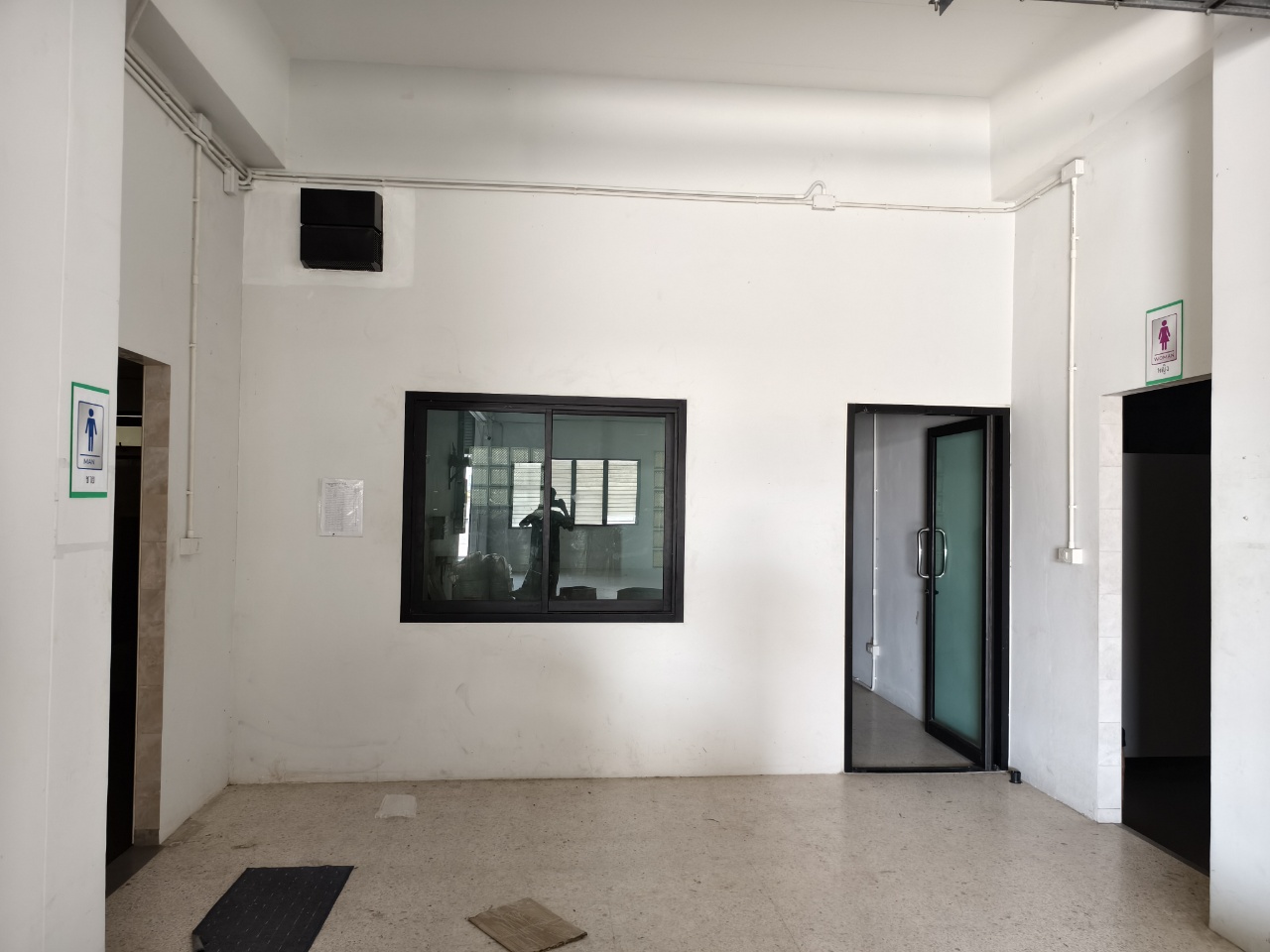 Warehouse for rent in Lat Krabang, Bangkok - Ground-floor lobby wall with internal viewing window and doors to offices and restrooms.