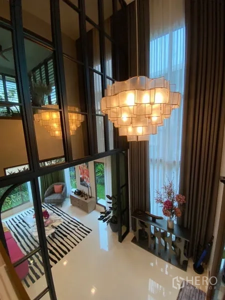 บ้าน ขายในBang Kapi, Bangkok - พื้นที่นั่งเล่นเพดานสูงสองชั้น พร้อมโคมไฟแชนเดอเลียร์ ผ้าม่านสูง และผนังกระจกเงา