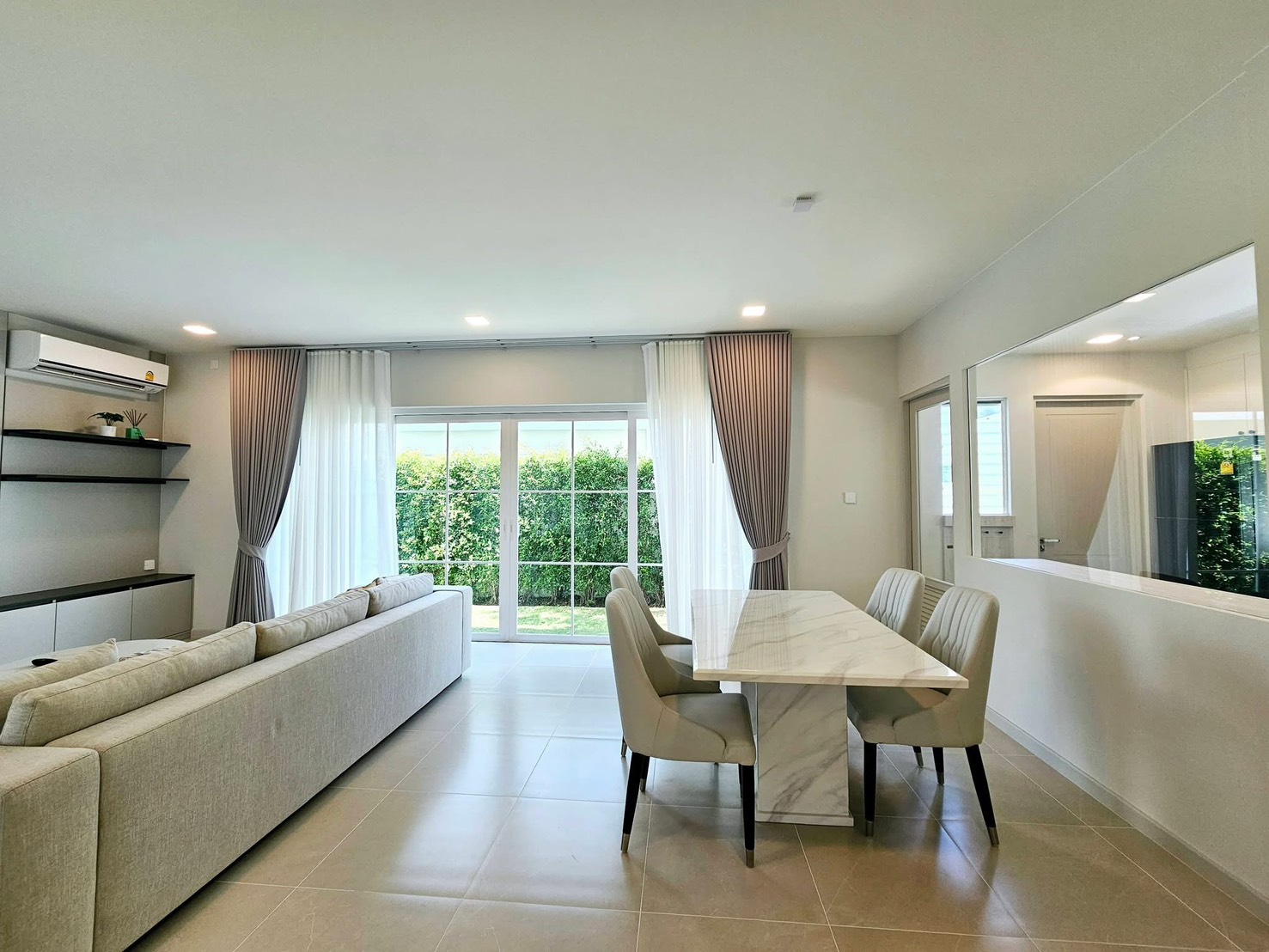 Detached House for rent in Bang Phli, Samut Prakan - Open living area with wall-mounted TV, L-shaped sofa, and dining set.