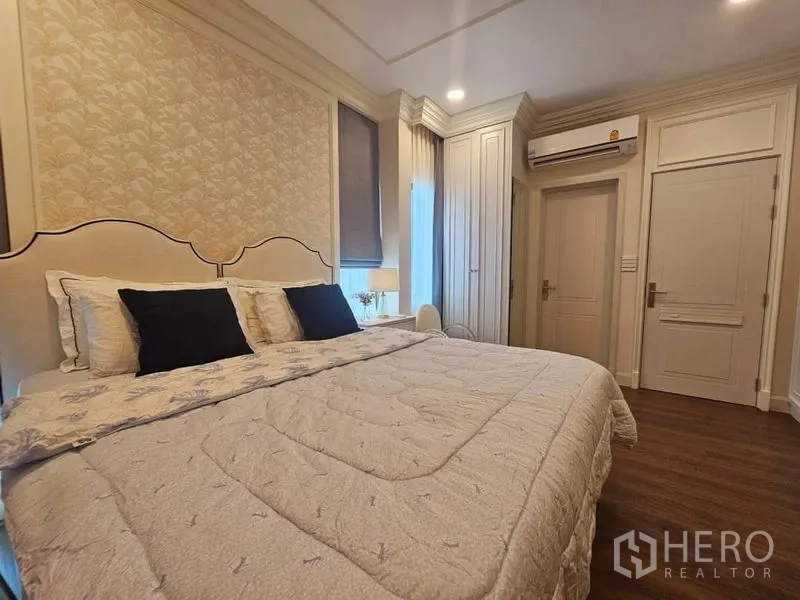 Detached House for rent or sale in Saphan Sung, Bangkok - Cozy bedroom with wallpapered headboard wall, built-in wardrobes and wood flooring.