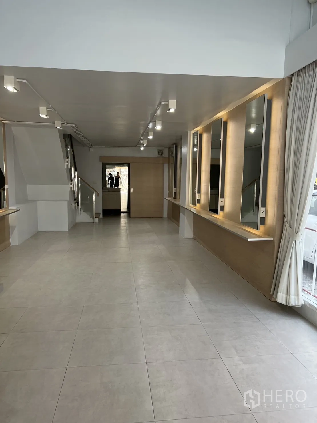 Shophouse for rent in Watthana, Bangkok - Open commercial area with track lighting, staircase and display mirrors along the wall.