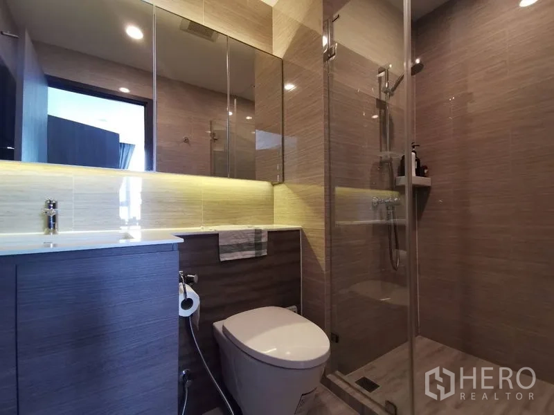 公寓 出售在Phra Khanong, Bangkok - 现代浴室，玻璃淋浴间、坐便器与带灯长台面。