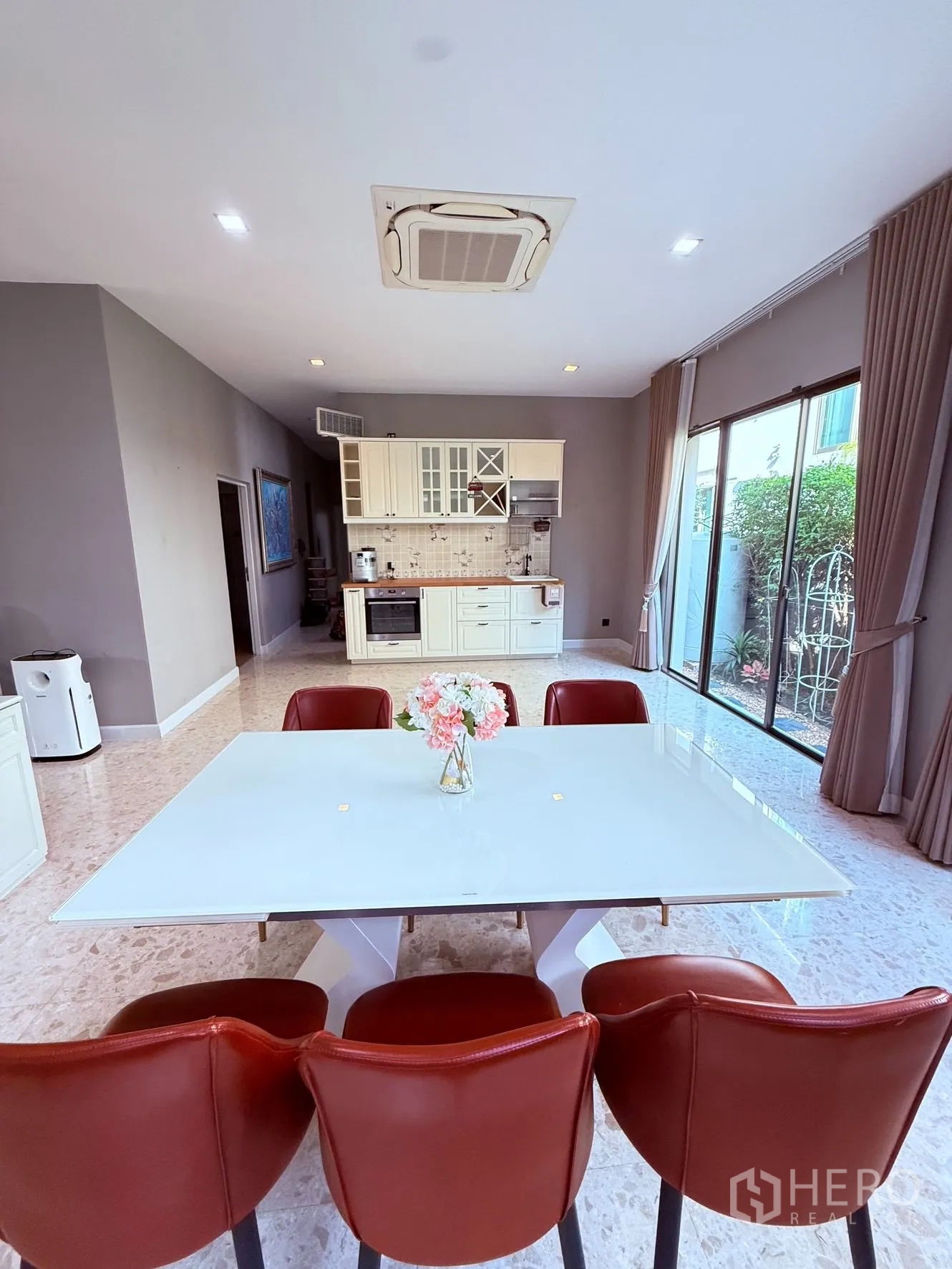 บ้านเดี่ยว for rent or sale in Prawet, Bangkok - มุมทานอาหารโต๊ะสีขาว เก้าอี้สีแดง ใกล้เคาน์เตอร์ครัวและประตูกระจกสไลด์.