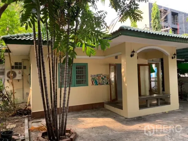 Detached House for rent in Khlong Toei, Bangkok - Angle view of the house showing palm trees, small terrace and driveway.