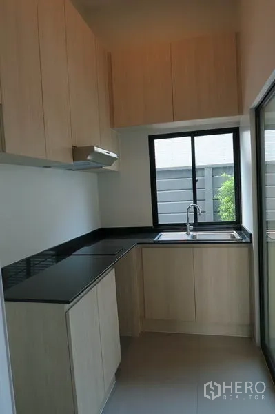 ทาวน์เฮาส์ ให้เช่าในSuan Luang, Bangkok - ครัวรูปตัวแอล ตู้ลายไม้ เคาน์เตอร์สีดำ หน้าต่างและอ่างล้างจาน