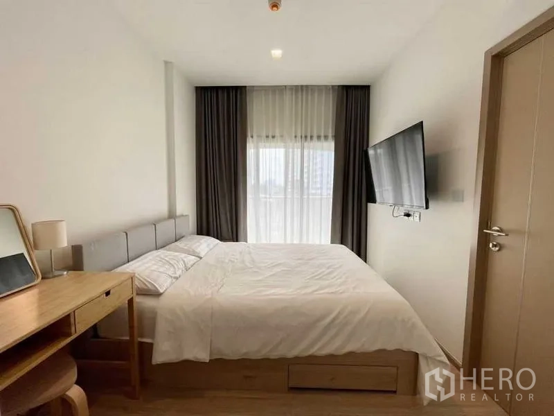 คอนโด ให้เช่าหรือขายในWatthana, Bangkok - ห้องนอนมินิมอล ผ้าม่านโปร่ง ทีวีติดผนัง และแสงธรรมชาติอ่อนๆ