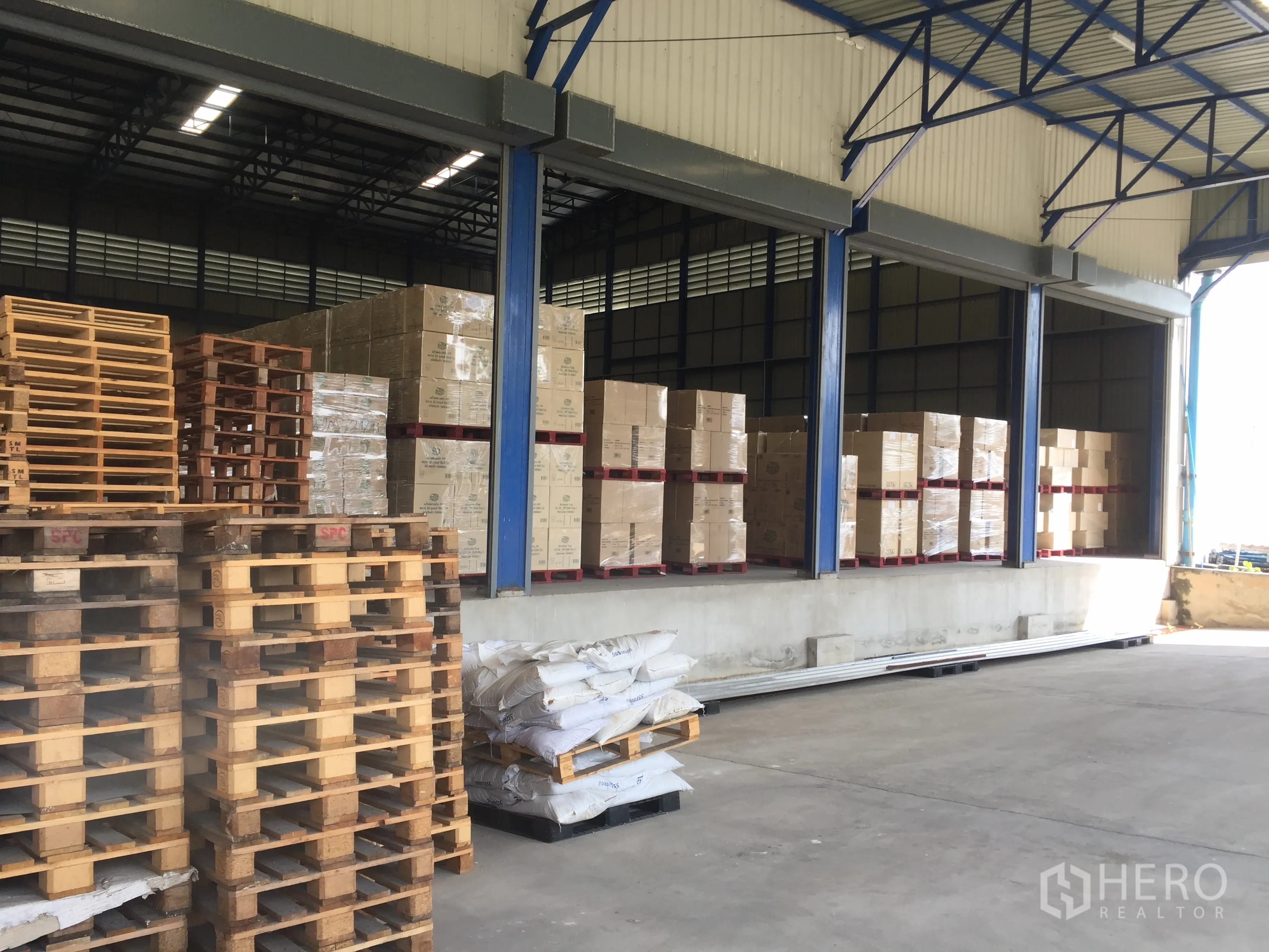 Warehouse for rent in Pak Kret, Nonthaburi - Multiple dock doors with pallets and carton boxes in a covered loading zone.