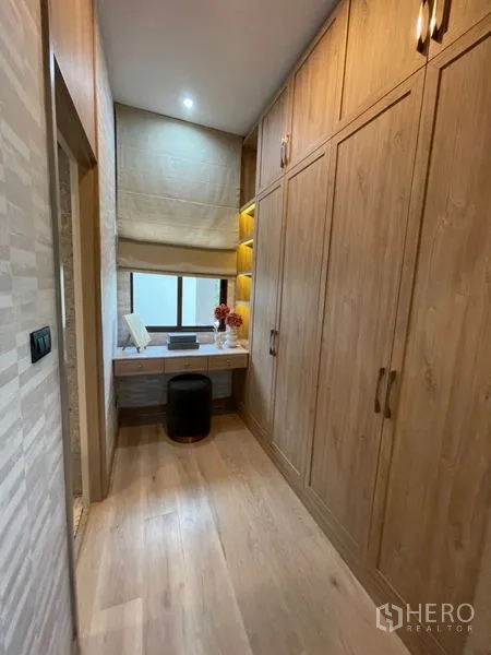 Detached House for sale in Bang Kapi, Bangkok - Walk-in wardrobe corridor with built-in wooden closets and dressing table.