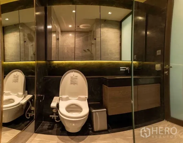 Condominium for rent - Modern bathroom with large mirrored wall, illuminated vanity and glass-enclosed shower.