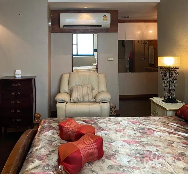 คอนโด ให้เช่าในKhlong Toei, Bangkok - มุมห้องนอนอบอุ่นพร้อมเก้าอี้เอนกาย ตู้เสื้อผ้ากระจก และโคมข้างเตียง