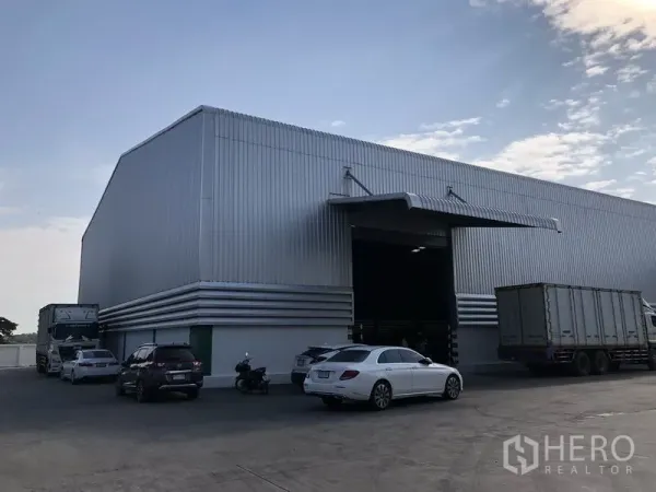 Warehouse for rent in Pathum Thani - Large metal-clad warehouse exterior with multiple loading bays and ample parking apron.