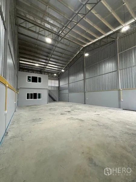 货栈 出租在Mueang Pathum Thani, Pathum Thani - 朝向办公室的纵深视角，高墙金属板与LED照明清晰可见。