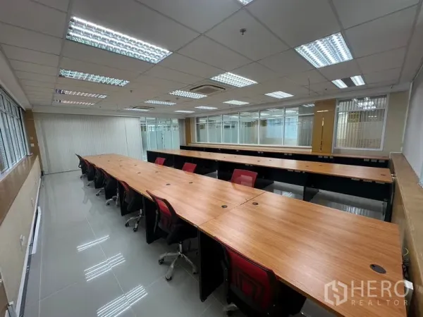 Office Space for rent in Suan Luang, Bangkok - Team workspace with two rows of collaborative desks, glass partitions, LED lighting and glossy tiled flooring in a Suan Luang office.