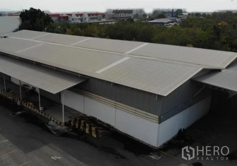 货栈 出租在Chon Buri - 春武里是拉差金属屋顶仓库航拍，带有顶棚装卸月台和卡车泊位。