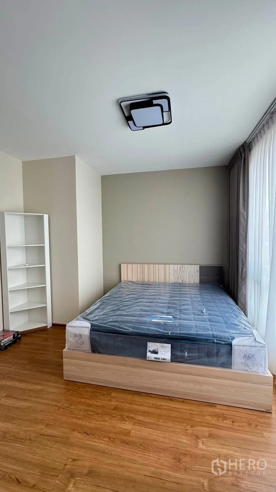 Townhouse for rent in Bang Phli, Samut Prakan - Spacious bedroom with double bed, tall window and a white bookshelf.