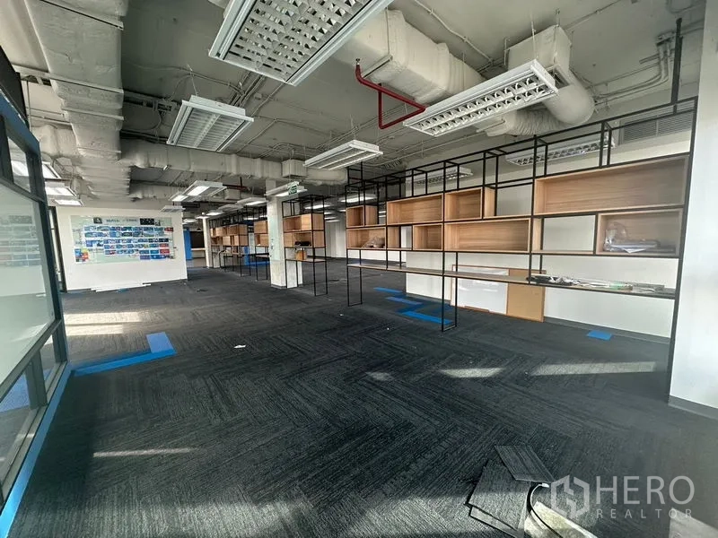 Office Space for rent in Bang Rak, Bangkok - Open workspace with metal-framed shelving units and carpet tiles.