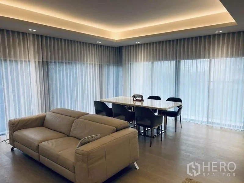 Condominium for rent in Pathum Wan, Bangkok - Living and dining area wrapped with sheer-curtained floor-to-ceiling windows.