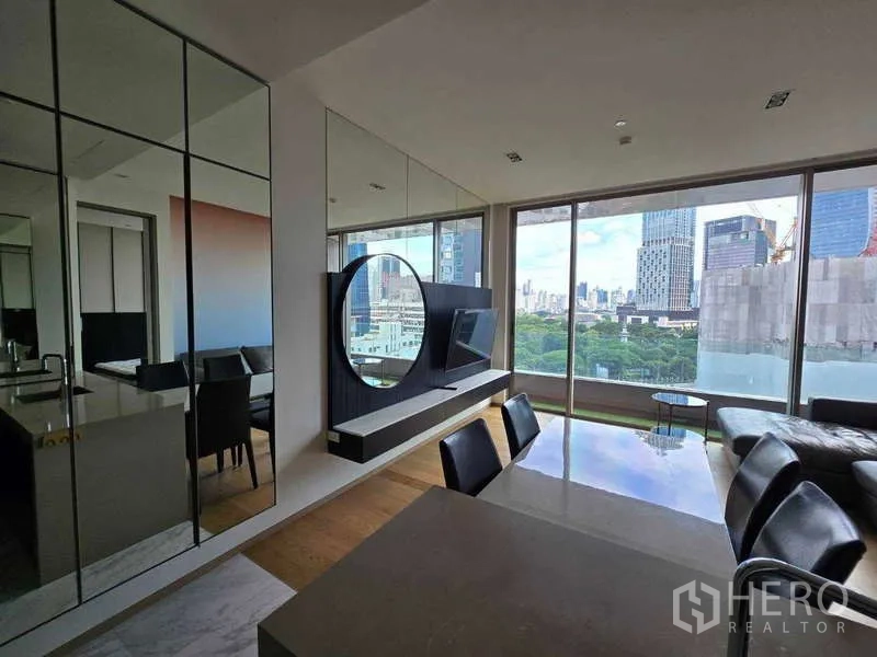 公寓 出租或出售在Bang Rak, Bangkok - 简洁客厅，镜面柜与圆形装饰墙，眺望城市天际线。