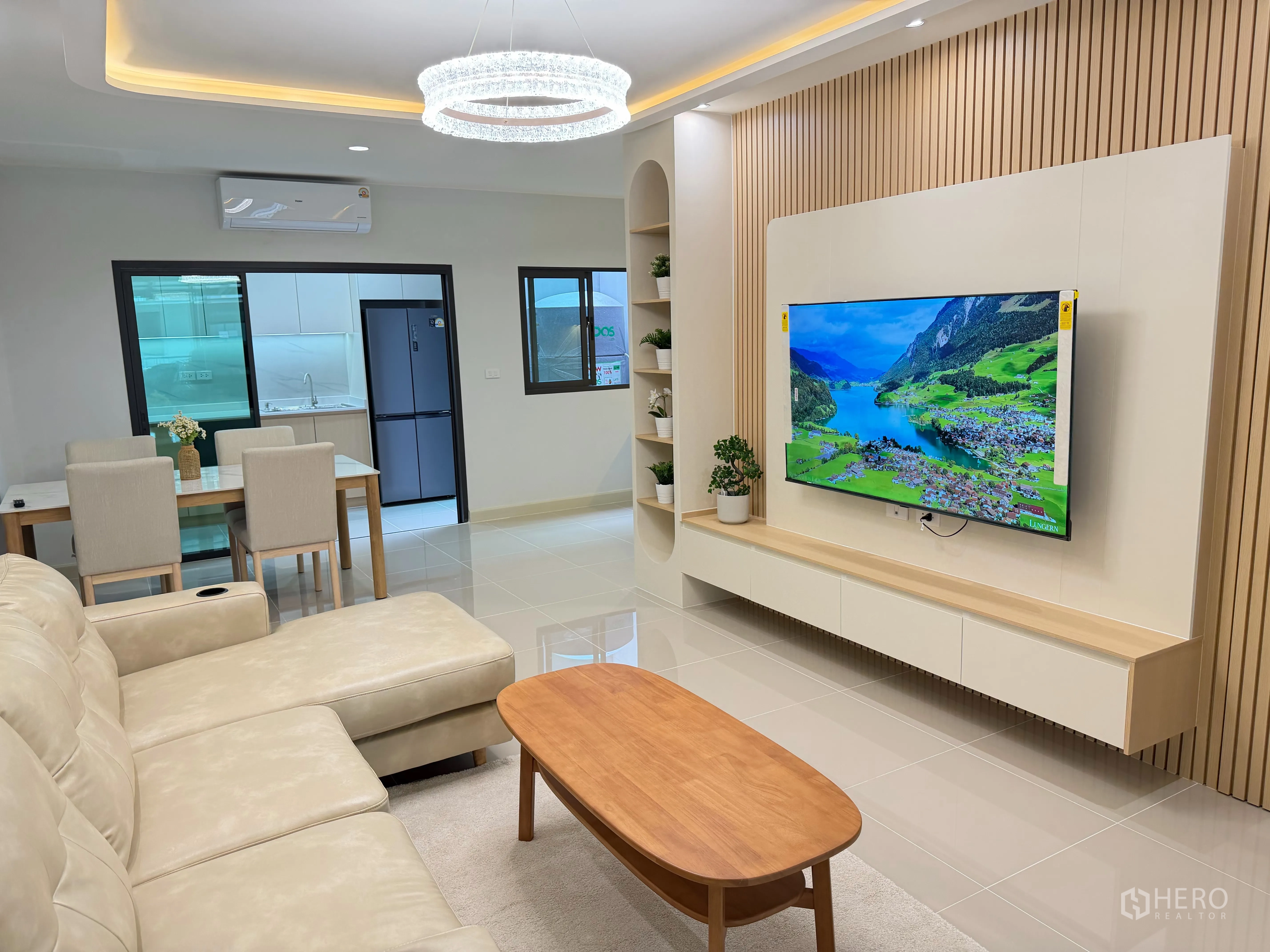 Townhouse for rent in Bang Phli, Samut Prakan - Living area with sectional sofa facing a mounted TV and dining set.