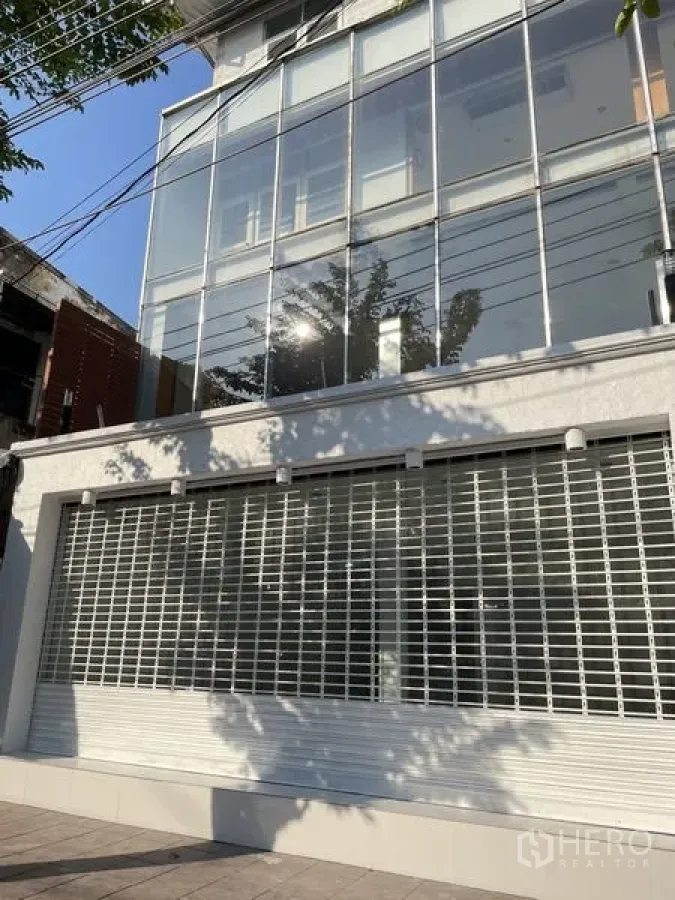 Shophouse for rent in Dusit, Bangkok - Multi‑storey shophouse facade featuring large glass panels and a metal security roller shutter on the ground floor.