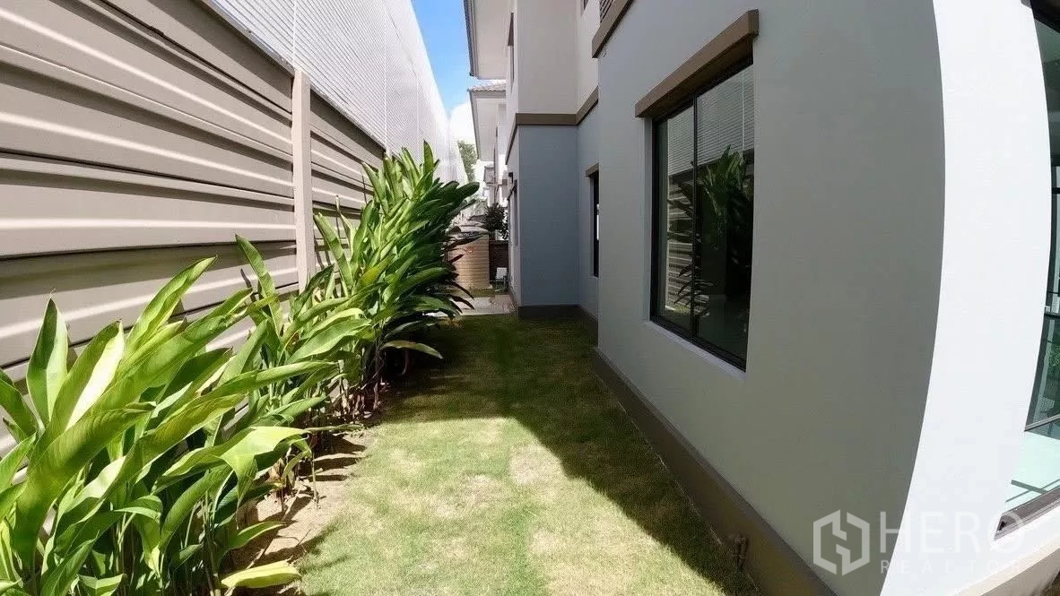 独立式住宅 出租或出售在Bang Phli, Samut Prakan - 另一侧院草坪，沿围栏种有热带植物。