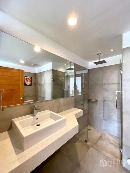 Townhouse for rent in Khlong Toei, Bangkok - Bathroom with glass shower enclosure and square basin countertop.