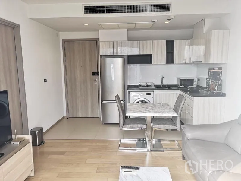 公寓 出租在Watthana, Bangkok - 开放式客厅与L形厨房，石纹餐桌与木地板。