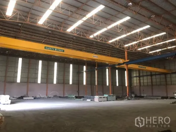 Home Office for sale in Khlong Luang, Pathum Thani - High-clear warehouse interior featuring overhead gantry cranes and skylight panels.