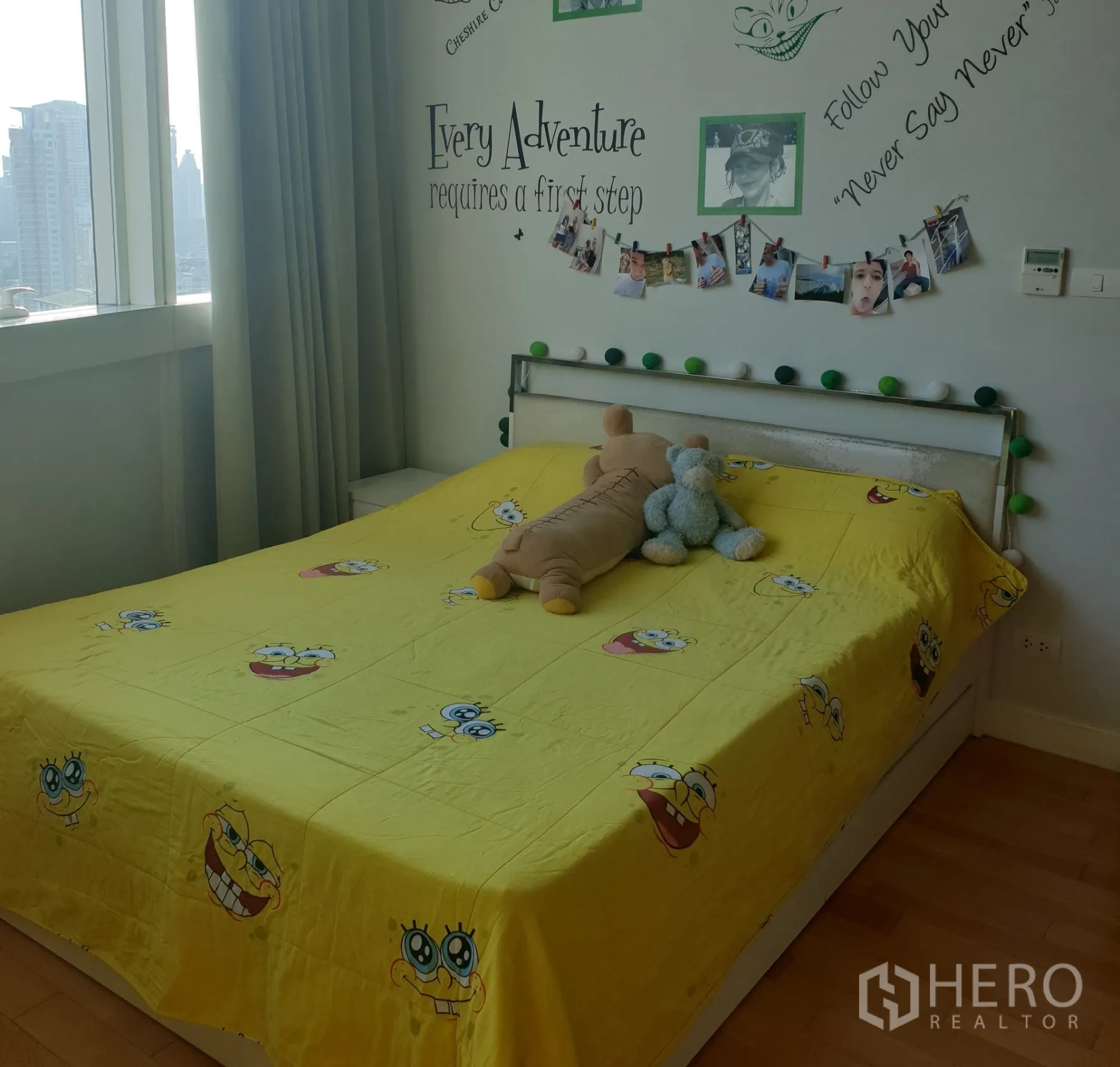 คอนโด ขายในKhlong Toei, Bangkok - ห้องนอนอบอุ่นมีหน้าต่างวิวเมือง ผนังตกแต่งข้อความ และเตียงควีนผ้าปูสีเหลือง