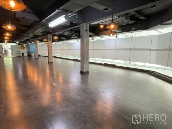 สำนักงาน ให้เช่าในRatchathewi, Bangkok - พื้นที่สำนักงานโอเพ่นสเปซกว้าง พื้นกระเบื้องสีเข้ม ฝ้าแบบลอยโชว์งานระบบ โคมไฟแขวน และผนังกระจกยาว