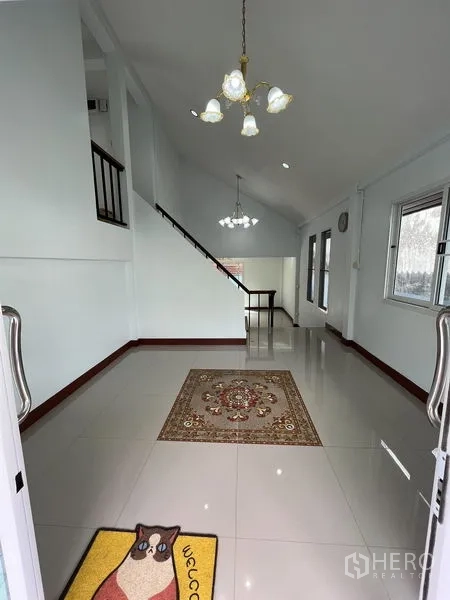 บ้าน ให้เช่าในKhlong Toei, Bangkok - พื้นที่นั่งเล่นเพดานสูง โคมไฟแชนเดอเรีย และบันไดขึ้นชั้นบน