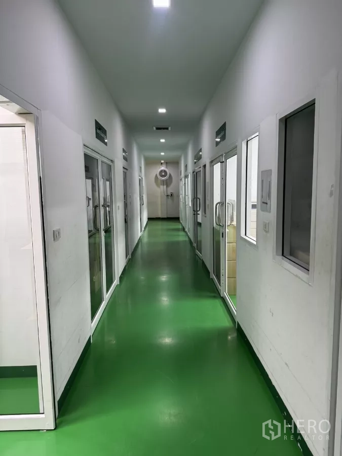 Factory for sale in Lam Luk Ka, Pathum Thani - Symmetrical corridor with green epoxy floor and multiple glass-door rooms on both sides.