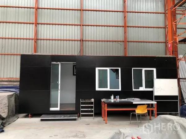 Warehouse for rent in Samut Prakan - Modular site office with windows and desks installed inside the warehouse.