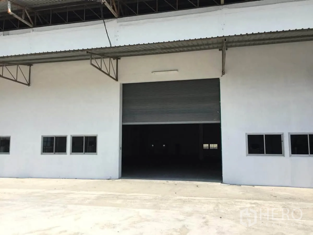 โกดัง for rent in Bang Sao Thong, Samut Prakan - ด้านหน้าพร้อมประตูม้วนกว้าง ช่องหน้าต่างหลายบาน และชายคาคลุมลานโหลด