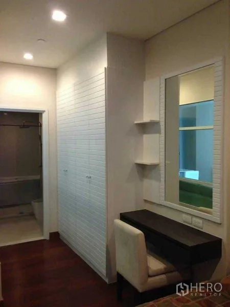 Condominium for rent or sale in Watthana, Bangkok - Dressing corridor with built-in wardrobes, wall mirror and desk, leading to the bathroom.