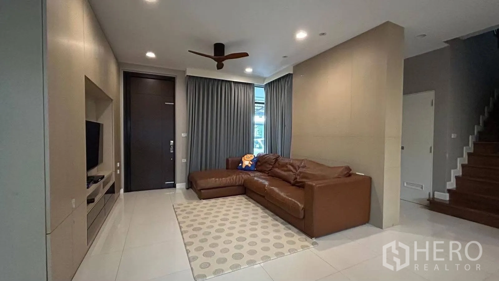 บ้านเดี่ยว for rent in Prawet, Bangkok - ห้องนั่งเล่นโซฟาหนังทรง L ผนังทีวี พัดลมเพดาน และบันไดขึ้นชั้นบน
