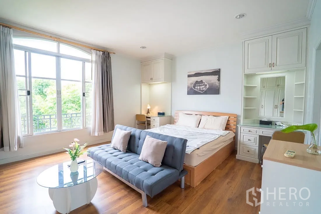 联排别墅 for rent in Yan Nawa, Bangkok - 明亮主卧，床尾沙发、飘窗与木地板。