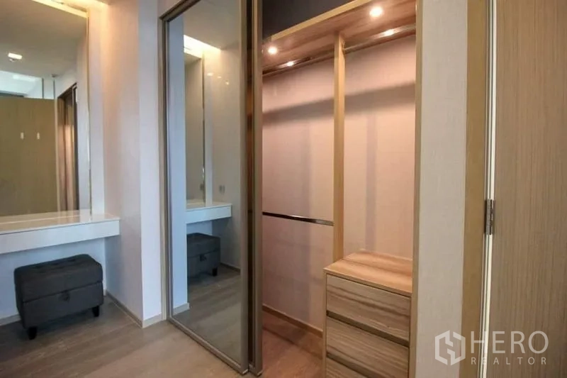 Condominium for sale in Watthana, Bangkok - Walk-in closet with mirrored sliding doors, built-in drawers and a dressing table.