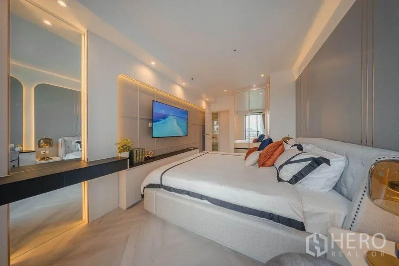 คอนโด ให้เช่า - ห้องนอนหลักมุมกว้าง ทีวีติดผนัง โต๊ะเครื่องแป้งลอย และหน้าต่างรับวิว