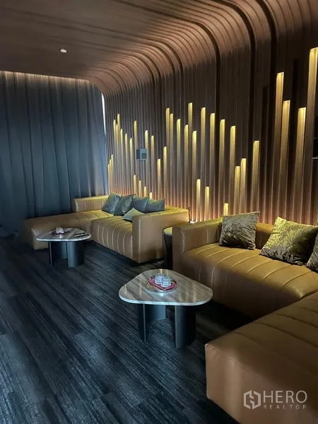 公寓 出租在Ratchathewi, Bangkok - 私密会客区，木质墙面与氛围灯，皮质沙发座。