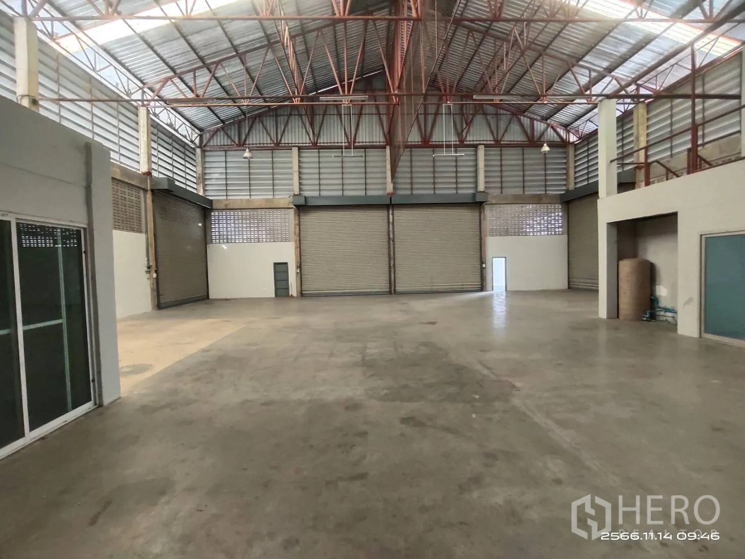Warehouse for rent in Khlong Sam Wa, Bangkok - Large warehouse interior with high steel-truss roof, concrete floor, and multiple roller shutter doors.